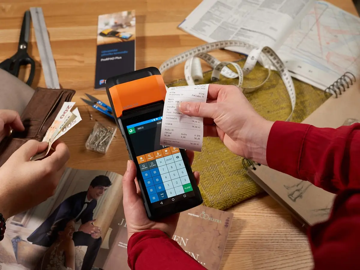 A customer paying by card on a handheld till, with a printed receipt