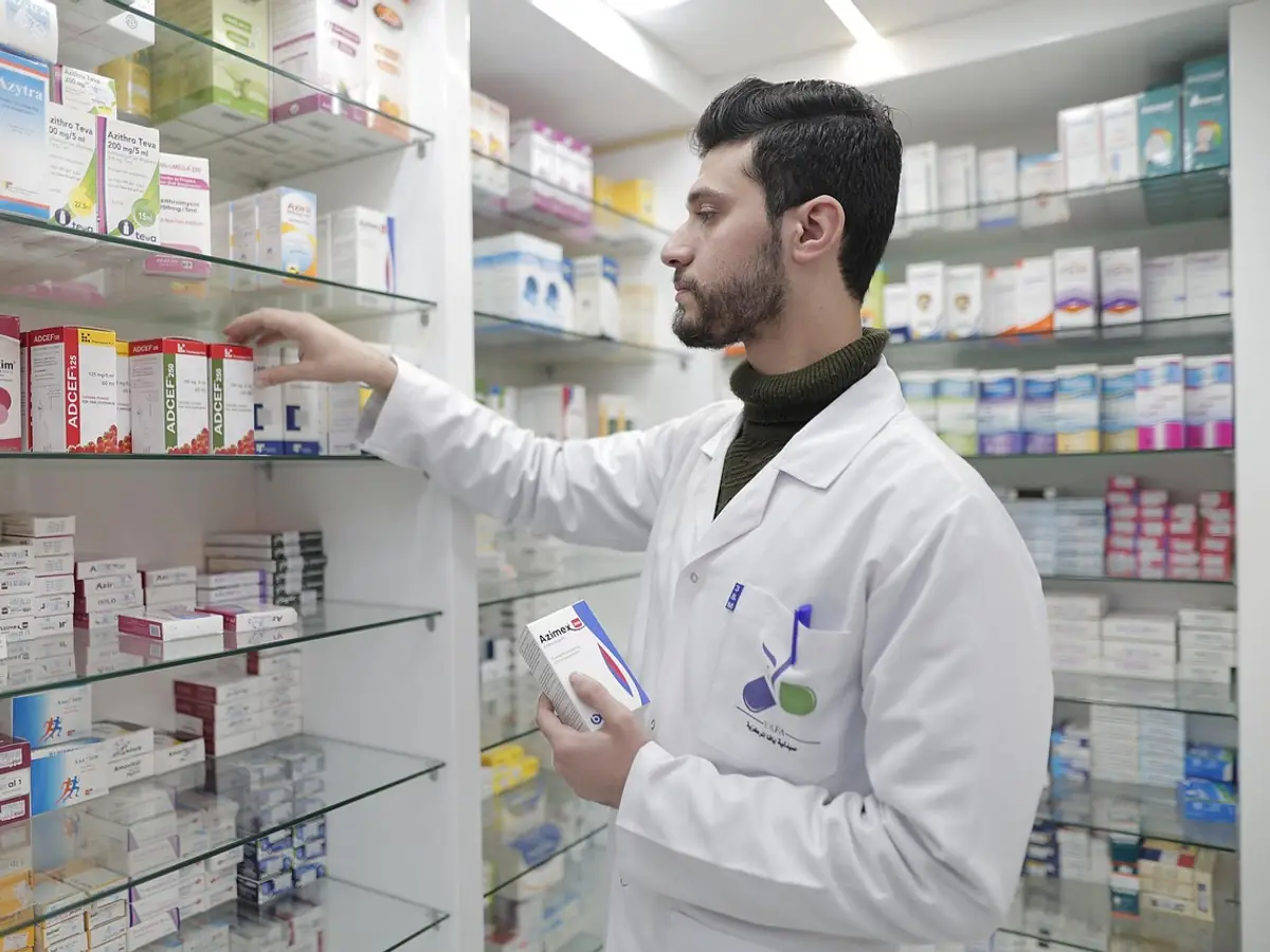 A pharmacist putting stock away on the pharmacy shelves