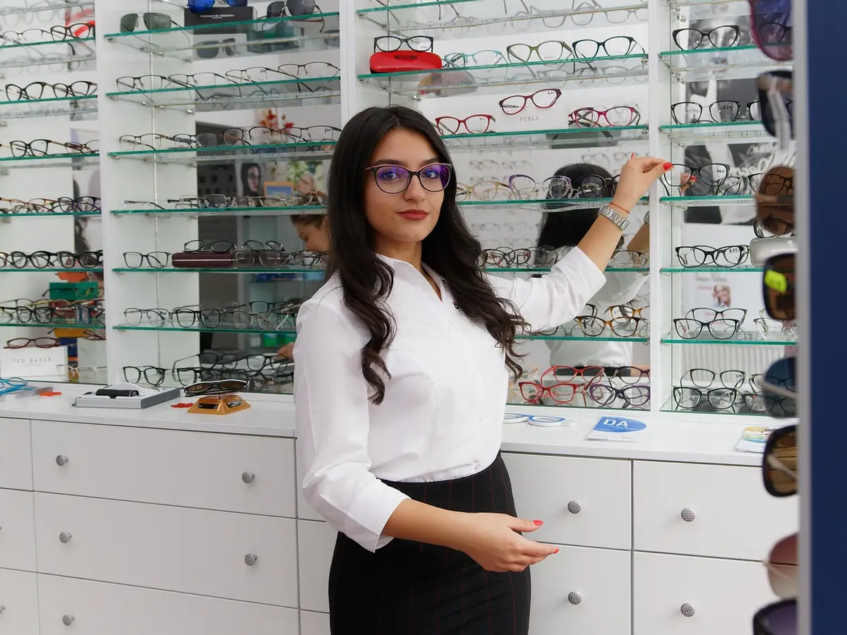 An optician arranging frames on the shelves of her shop